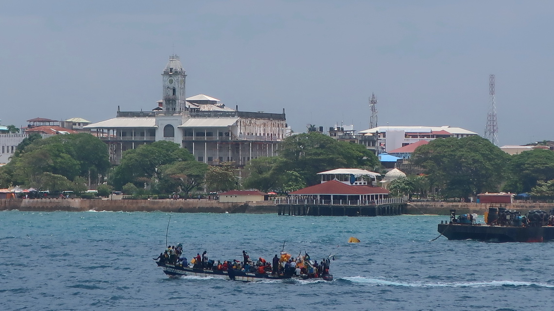 Crowded boat with Sultans Palace of Stone Town