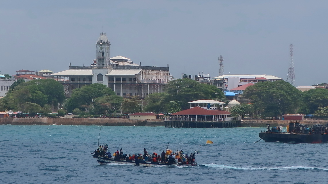 Crowded boat with Sultans Palace of Stone Town